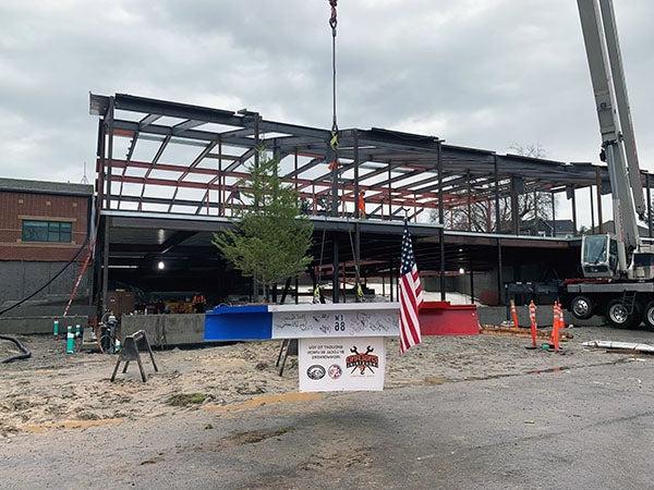 final structural steel beam is painted red, white, and blue; has signatures on the white part; has flag and evergreen tree attached