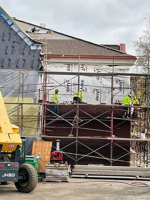 people on a scaffolding putting brick on a building