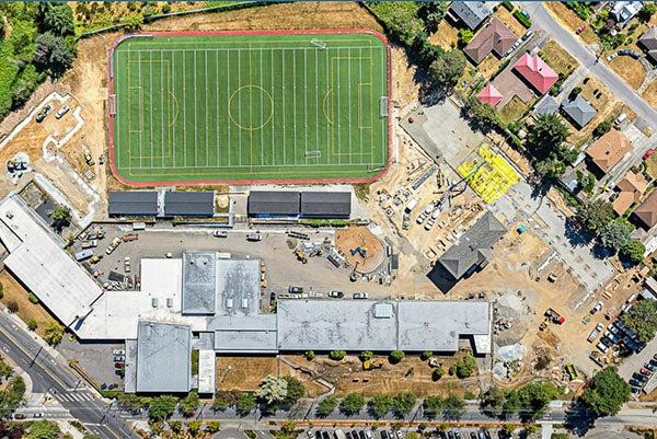 aerial view of a large field with a building on one side and construction underway next to it