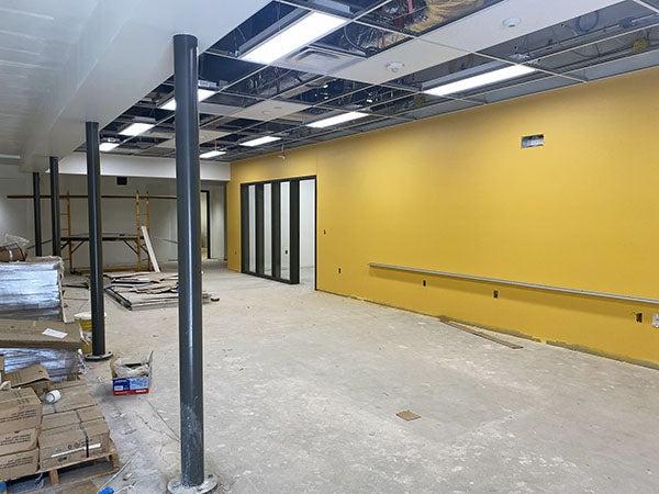 a large yellow wall in a large room with no floor coverings or ceiling tiles