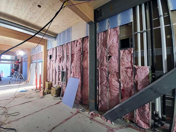 pink insulation shows between metal studs with some wallboard above it