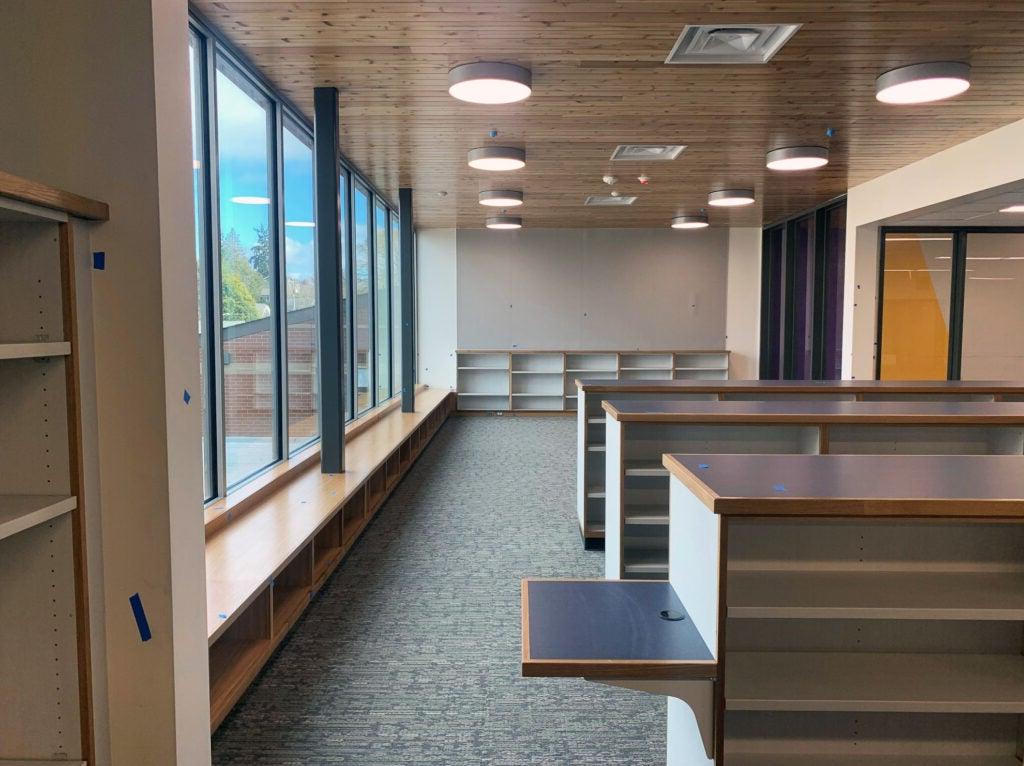 an empty library with shelves, windows, and a bench under the windows